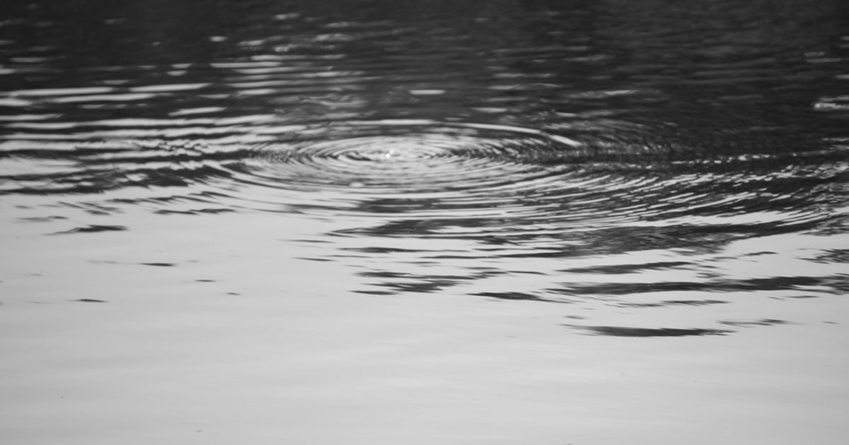 Ripples spreading across still water, in black and white.